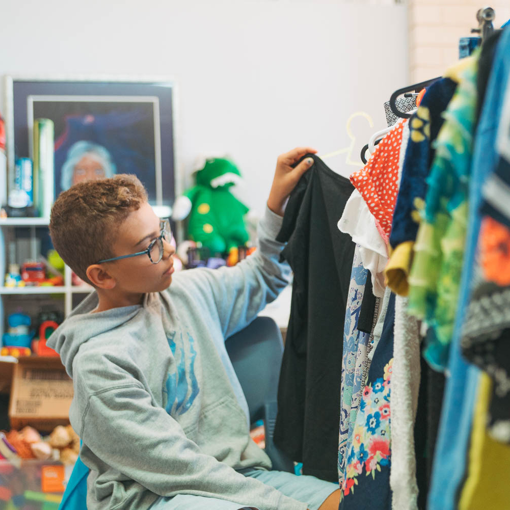 Boy in Op Shop going through donated clothes.